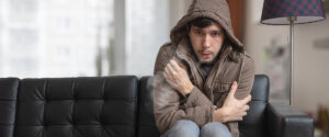 Cold Weather in Georgia: Keeping Your Home Warm and Efficient This Winter - shivering man sitting on sofa