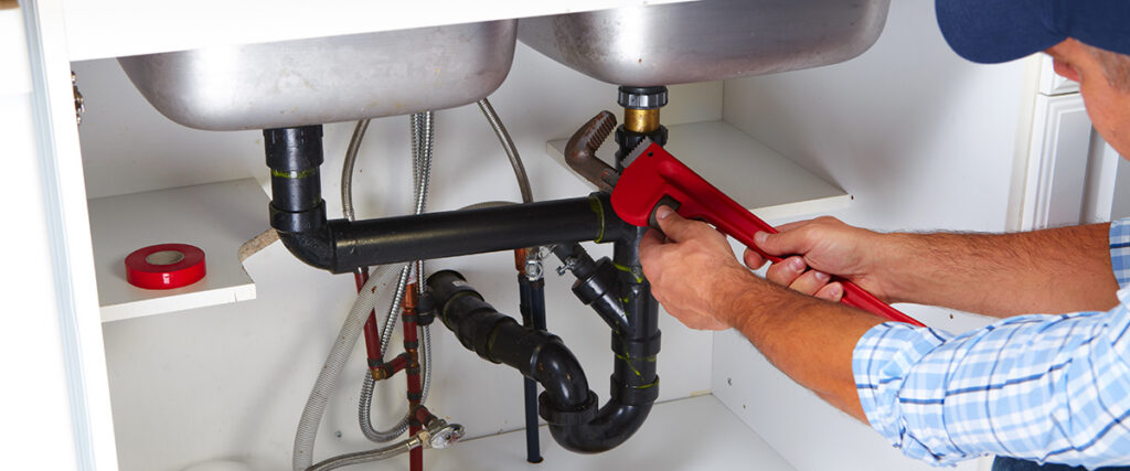 Plumber with Plumbing tools on the kitchen. Renovation.